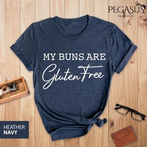 May include: A heather navy blue t-shirt with the text "My Buns Are Gluten Free" in white.