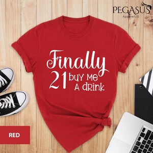 May include: Red t-shirt with white text that says "Finally 21 buy me a drink".