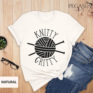 May include: White t-shirt with a black graphic of a ball of yarn and knitting needles. The text "Knitty Gritty" is written above and below the graphic.