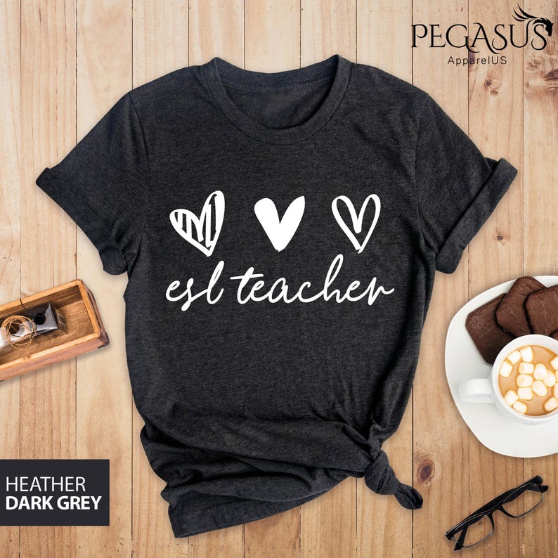 May include: Dark heather grey t-shirt with three white hearts and the text "esl teacher" in white.