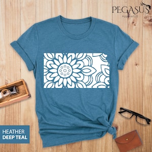 May include: A heather deep teal t-shirt with a white outline of the state of Kansas featuring a mandala design. The text "PEGASUS ApparelUS" is in the top right corner of the image.