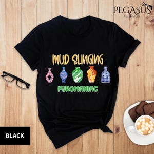 May include: Black t-shirt with the text "Mud Slinging Pyromaniac" and a row of five colorful pottery vases.