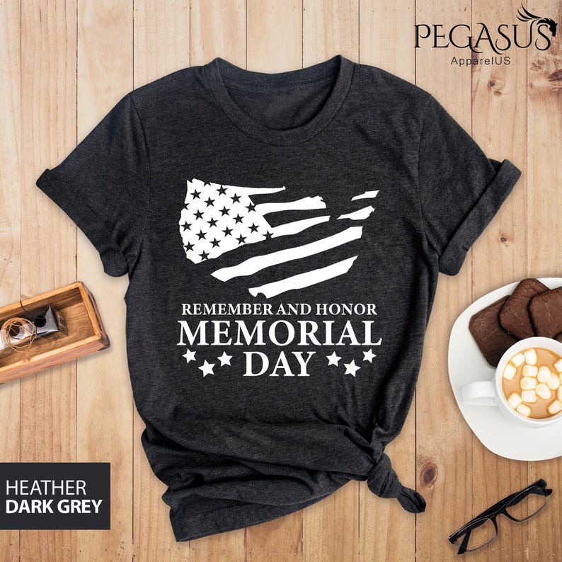 Peut inclure: T-shirt gris fonc&eacute; chin&eacute; avec un contour blanc du drapeau am&eacute;ricain et le texte "Remember and Honor Memorial Day" avec trois &eacute;toiles de chaque c&ocirc;t&eacute; du mot "Day".