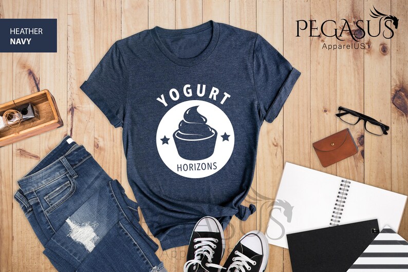 May include: A heather navy blue t-shirt with a white circle graphic that says "Yogurt Horizons" and features a stylized image of a yogurt cup with a swirl of yogurt on top.