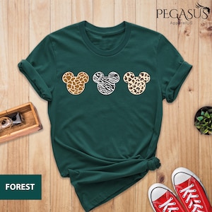 May include: A green t-shirt with a print of three Mickey Mouse heads. Each head is a different animal print: giraffe, zebra, and leopard.