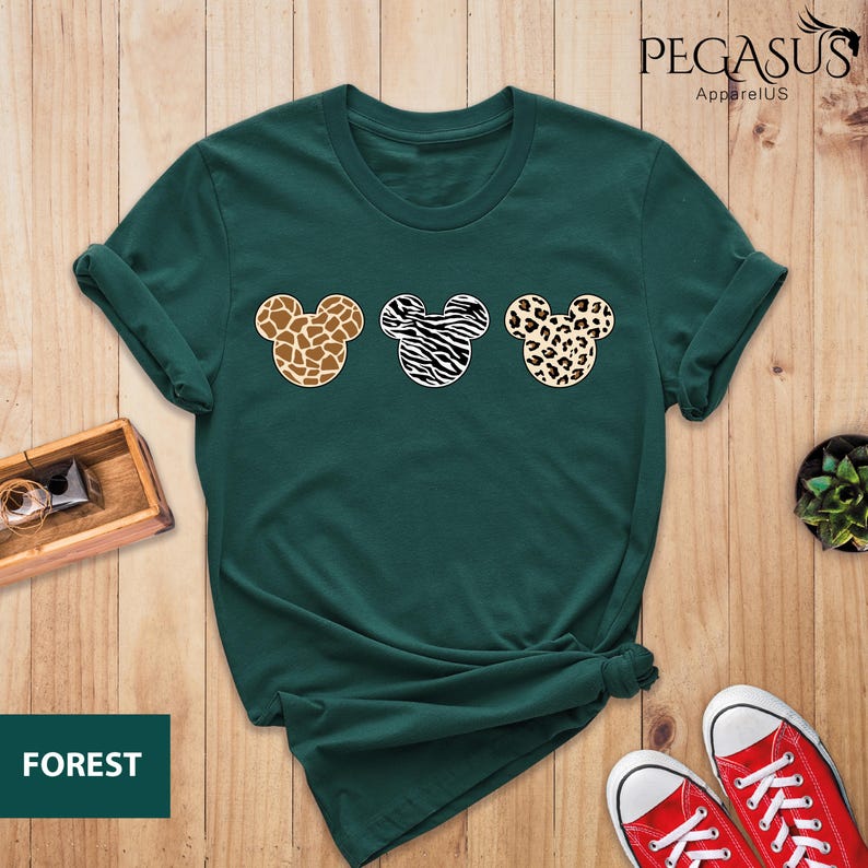 May include: A green t-shirt with a print of three Mickey Mouse heads. Each head is a different animal print: giraffe, zebra, and leopard.