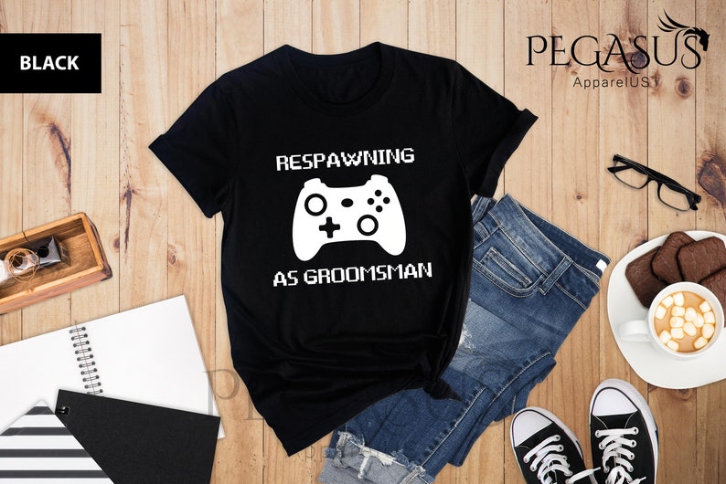 May include: Black t-shirt with a white graphic of a video game controller and the text "Respawning as groomsman".