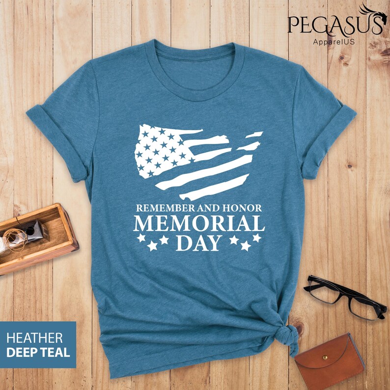 Peut inclure: Un t-shirt bleu avec un contour blanc du drapeau des &Eacute;tats-Unis et le texte "Remember and Honor Memorial Day" avec trois &eacute;toiles de chaque c&ocirc;t&eacute; du mot "Day".