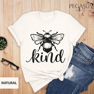 May include: White t-shirt with a black bee graphic and the word "kind" printed below it.