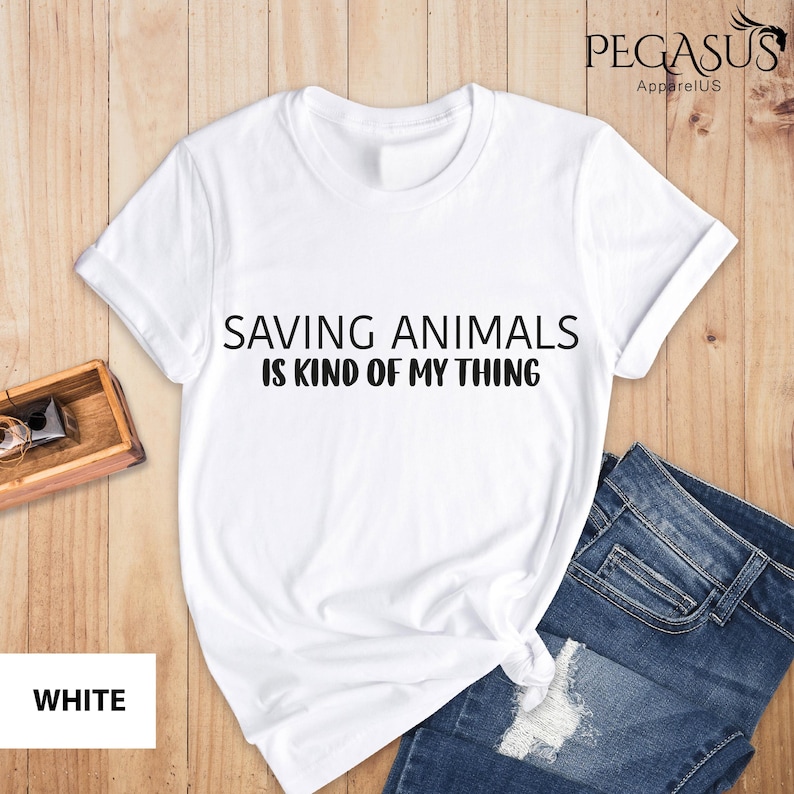 May include: White t-shirt with the text "Saving Animals is Kind of My Thing" printed in black.