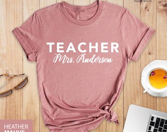May include: A heather mauve t-shirt with the text "TEACHER Mrs. Anderson" printed in white on the front.