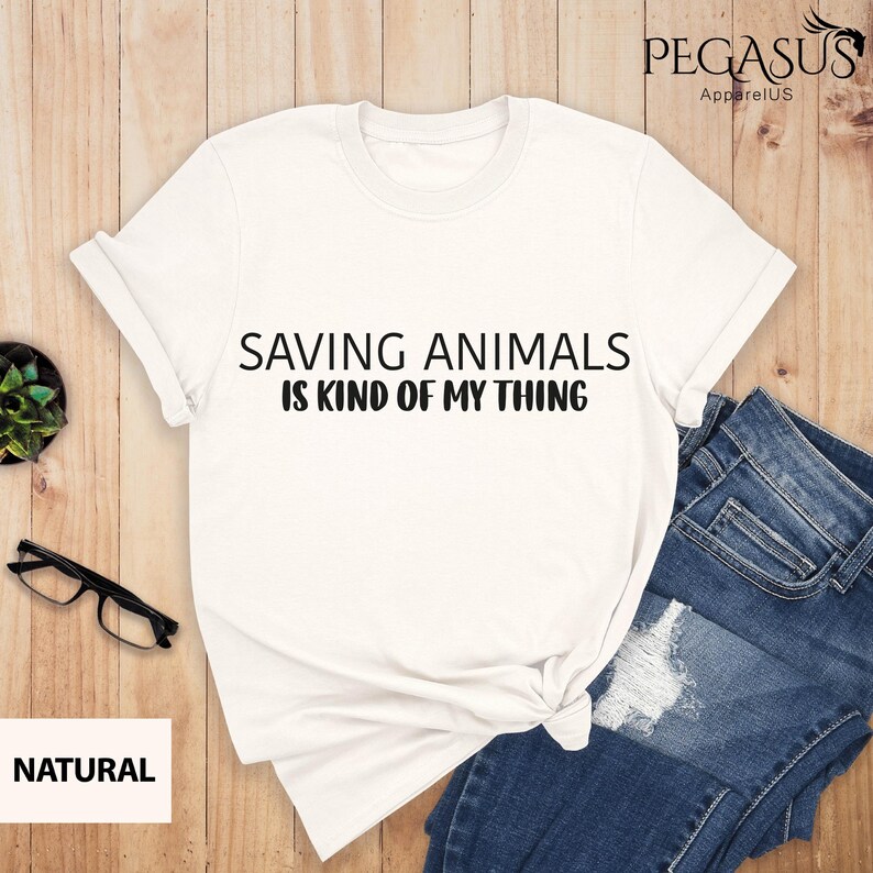 May include: White t-shirt with the text "Saving Animals is Kind of My Thing" printed in black.