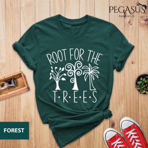 May include: A dark green t-shirt with a white graphic that says "Root for the Trees" with a stylized image of three trees.