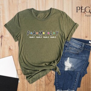 May include: A green t-shirt with the word "FAMILY" in white letters with colorful stars. The text "NAME:1 NAME:2 NAME:3 NAME:4" is printed below the word "FAMILY".