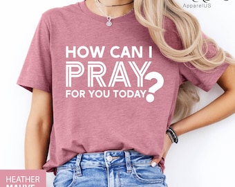 May include: Heather mauve t-shirt with the text "HOW CAN I PRAY FOR YOU TODAY?" in white. The shirt is a short-sleeved crew neck style. The words are stacked vertically, with a question mark at the end of the word "PRAY".