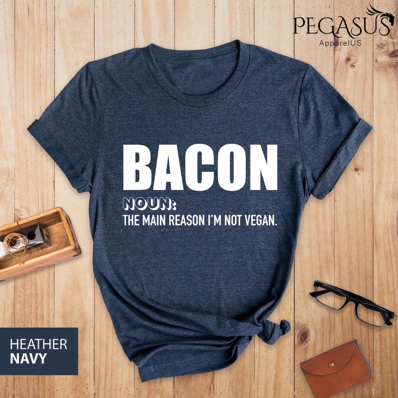 May include: A dark blue t-shirt with white text that reads "BACON NOUN: THE MAIN REASON I'M NOT VEGAN."