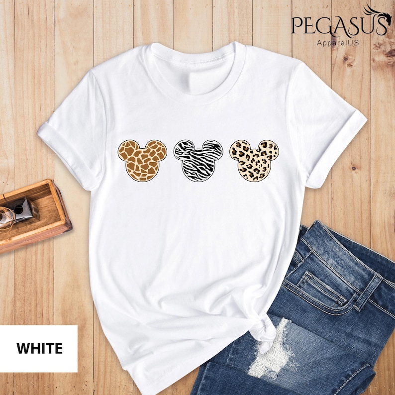 May include: White t-shirt with three Mickey Mouse heads in a row. Each head is a different animal print: giraffe, zebra, and leopard.