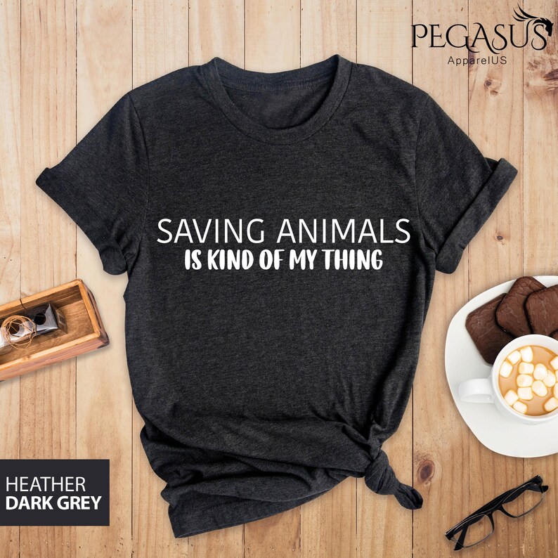May include: A dark heather grey t-shirt with the text "Saving Animals is Kind of My Thing" printed in white.