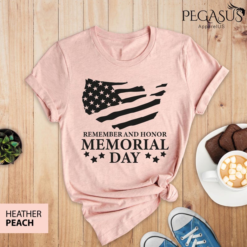 Peut inclure: Un t-shirt en p&ecirc;che bruy&egrave;re avec un motif de drapeau am&eacute;ricain noir et blanc et le texte "Remember and Honor Memorial Day" avec trois &eacute;toiles de chaque c&ocirc;t&eacute; du mot "Day".