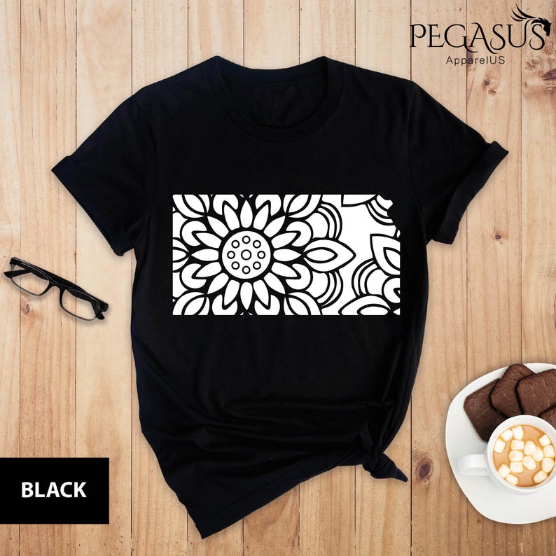 May include: Black t-shirt with a white mandala design in the shape of the state of Kansas.