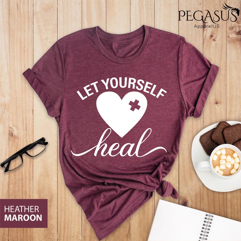May include: Heather maroon t-shirt with white text that reads "Let Yourself Heal" and a white heart with a white plus sign over it.