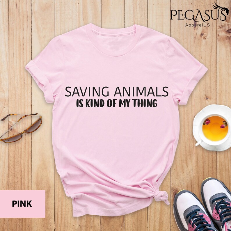 May include: Pink t-shirt with the text "Saving Animals is Kind of My Thing" printed on the front.