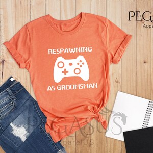 May include: Heather orange t-shirt with a white graphic of a video game controller and the text "Respawning as groomsman".
