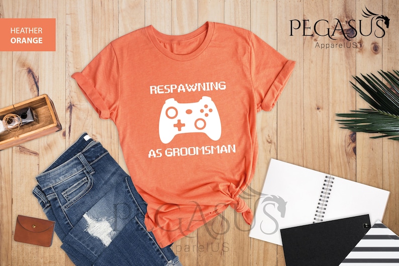 May include: Heather orange t-shirt with a white graphic of a video game controller and the text "Respawning as groomsman".