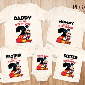 May include: A collection of white t-shirts and a onesie featuring a Mickey Mouse design for a second birthday. The shirts have text that says "Daddy", "Mommy", "Brother", and "Sister" with the number "2" and the word "Boy".