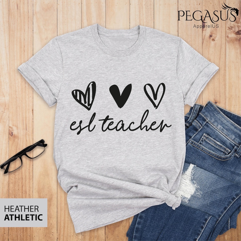 May include: Gray t-shirt with three black hearts and the text "esl teacher" in black.