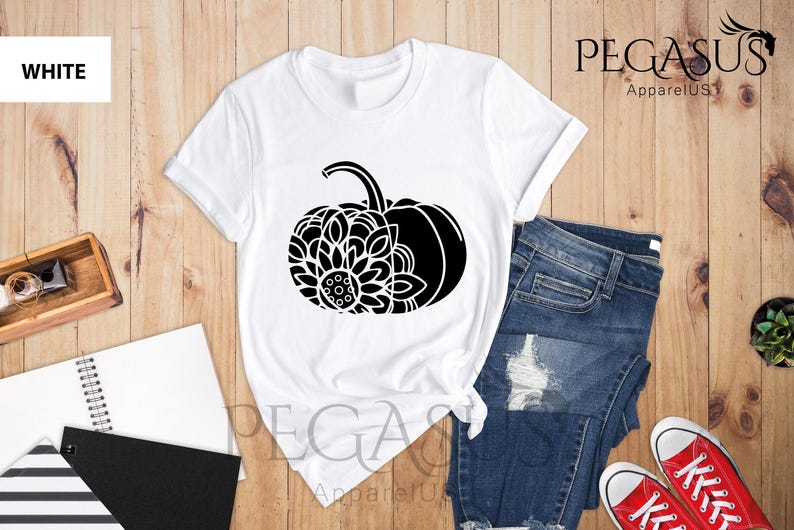 May include: White t-shirt featuring a black and white graphic of a pumpkin with a floral design. The text "PEGASUS ApparelUS" is visible in the top right corner of the image.
