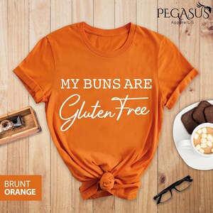 May include: Orange t-shirt with the text "My buns are gluten free" in white lettering.