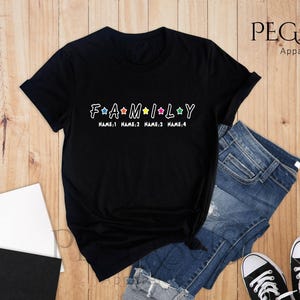 May include: Black t-shirt with a white graphic that says "FAMILY" with stars and the text "NAME 1 NAME 2 NAME 3 NAME 4".