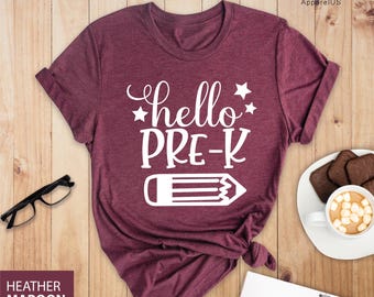 May include: A heather maroon t-shirt with the text "hello pre-k" and a white pencil graphic.