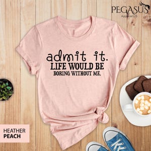 May include: A pink t-shirt with the text "admit it. LIFE WOULD BE BORING WITHOUT ME." printed in black.
