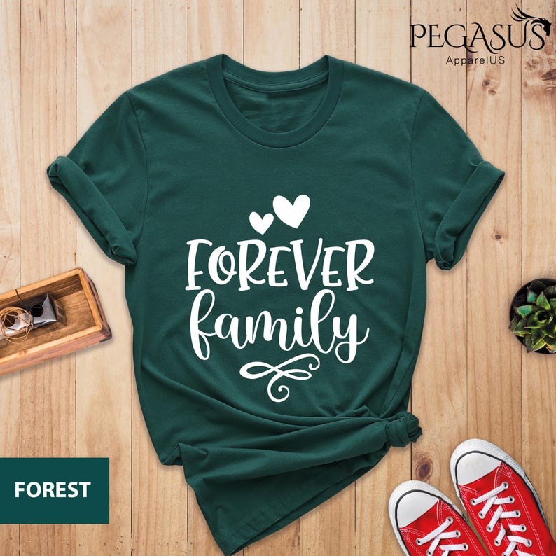 Pode incluir: Uma camiseta verde escura com o texto "FOREVER family" em letras brancas. O texto est&aacute; em uma fonte cursiva e &eacute; acompanhado por tr&ecirc;s cora&ccedil;&otilde;es brancos.