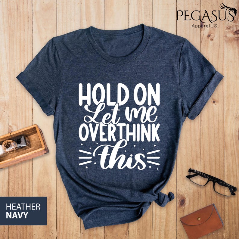 May include: A dark blue t-shirt with white text that reads "Hold on Let me overthink this".
