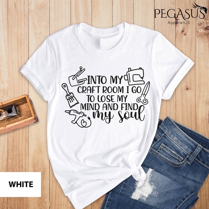 K&ouml;nnte beinhalten: Wei&szlig;es T-Shirt mit einer schwarzen Grafik, auf der "Into my craft room I go to lose my mind and find my soul" steht. Die Grafik enth&auml;lt Bilder eines Pinsels, einer N&auml;hmaschine, einer Hei&szlig;klebepistole und einer Schere.