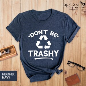May include: A heather navy blue t-shirt with a white graphic that says "Don't Be Trashy" with a recycling symbol.