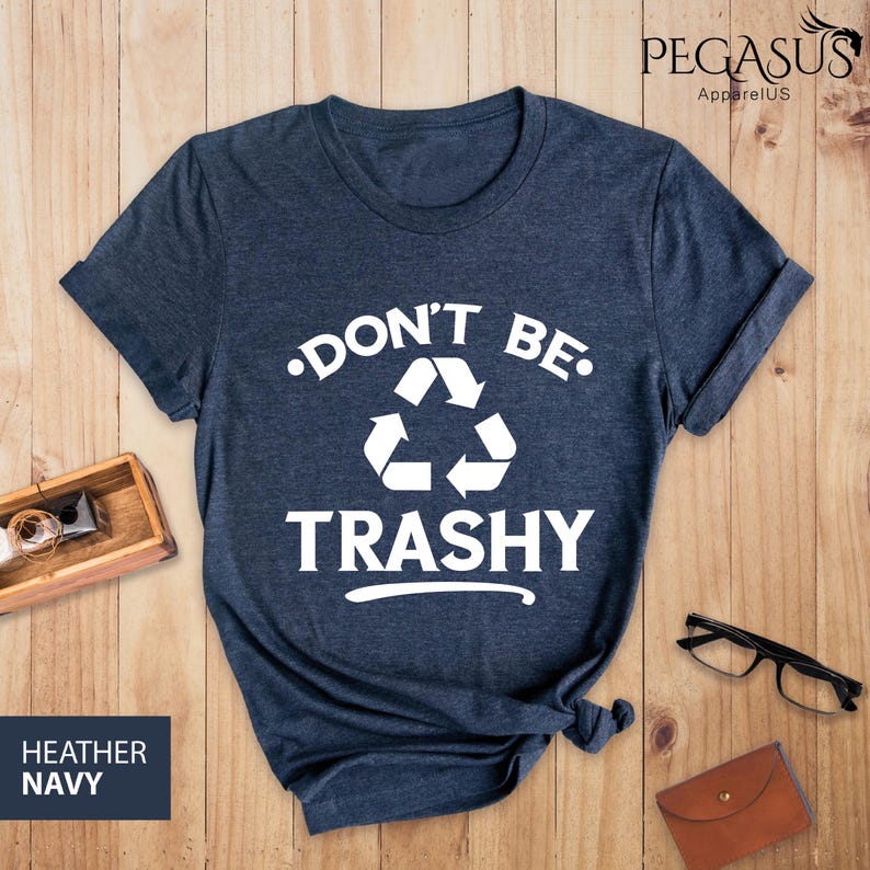 May include: A heather navy blue t-shirt with a white graphic that says "Don't Be Trashy" with a recycling symbol.