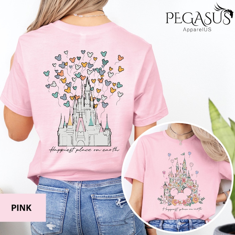 Op de afbeelding: Roze T-shirt met een afbeelding van een kasteel en ballonnen met de tekst "Happiest place on earth".