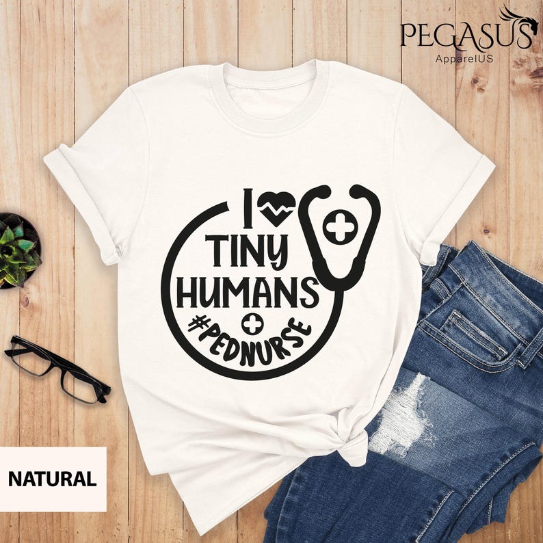 Op de afbeelding: Wit T-shirt met een zwarte afbeelding met de tekst "I love tiny humans #pednurse" met een stethoscoop en een hartontwerp.