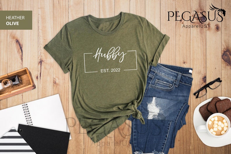 May include: A green heather olive t-shirt with the text "Hubby Est. 2022" in a white box.