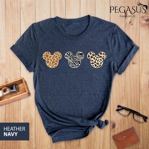 May include: Heather navy blue t-shirt with three Mickey Mouse heads in a row. Each head is a different animal print: giraffe, zebra, and leopard.