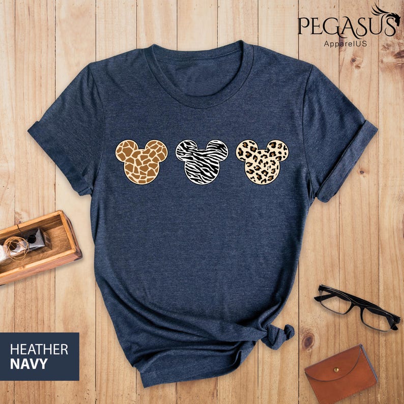 May include: Heather navy blue t-shirt with three Mickey Mouse heads in a row. Each head is a different animal print: giraffe, zebra, and leopard.