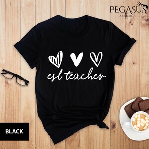 May include: Black t-shirt with three white hearts and the text "est teacher" in white.