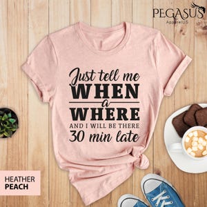Puede incluir: Una camiseta rosa con el texto "Just tell me WHEN a WHERE and I will be there 30 min late" impreso en negro.