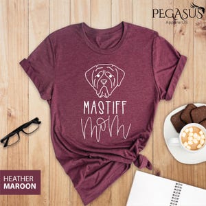 K&ouml;nnte beinhalten: Heather-marronfarbenes T-Shirt mit einer wei&szlig;en Umrandung eines Mastiff-Hunde-Kopfes und dem Text "Mastiff Mom" in Wei&szlig;.
