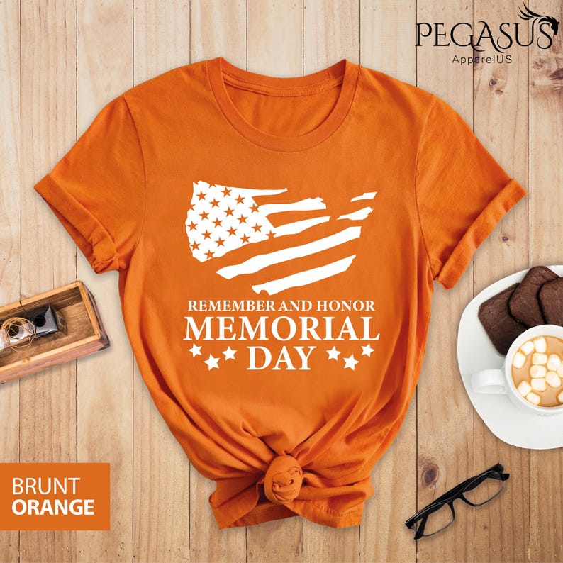 Peut inclure: T-shirt orange avec un graphique blanc d'un drapeau am&eacute;ricain en d&eacute;tresse et le texte "Remember and Honor Memorial Day" avec des &eacute;toiles.