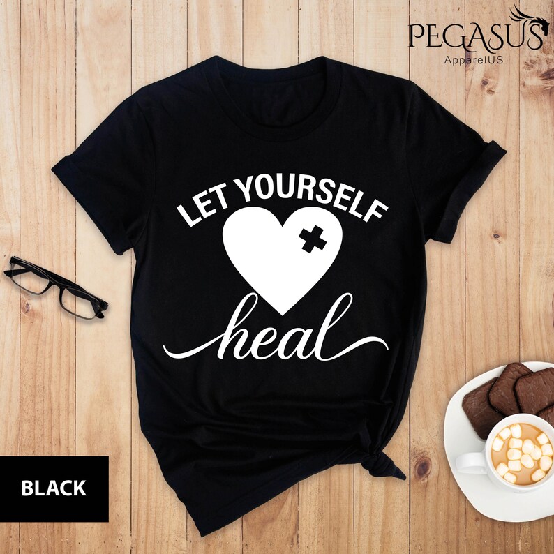 May include: Black t-shirt with white text that reads "Let yourself heal" and a white heart with a white plus sign over the broken part of the heart.